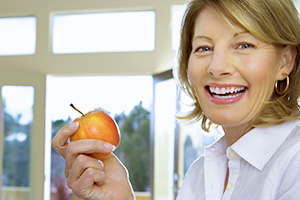 Implant Supported Dentures lady smiling with apple